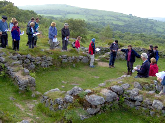 PDAS members look at longhouse at Hound Tor Medieval Village